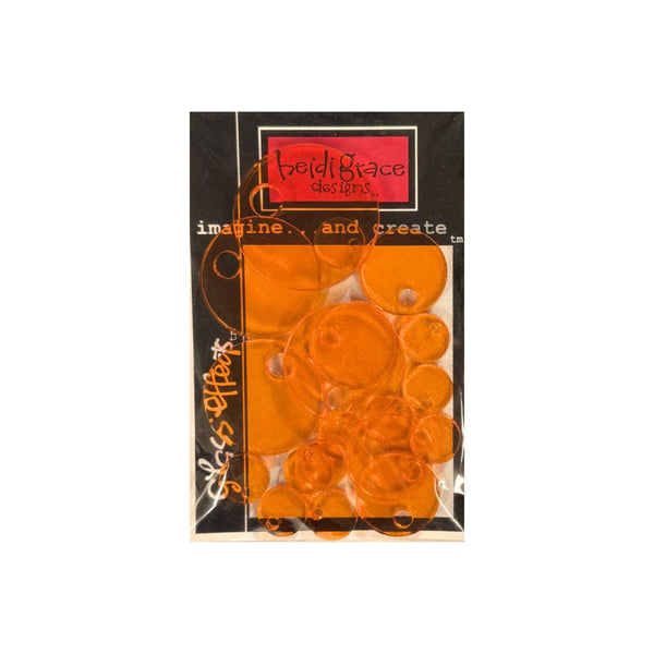 Heidi Grace Imagine & Create Elements - Circle Charms Orange translucent circular acrylic block in a black and clear plastic packaging, shown against a plain white background.