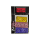 A packaged set of three embossed acrylic tiles  featuring the words 'happy', 'spring',  in yellow, pink, and purple, respectively, on a black backing card.