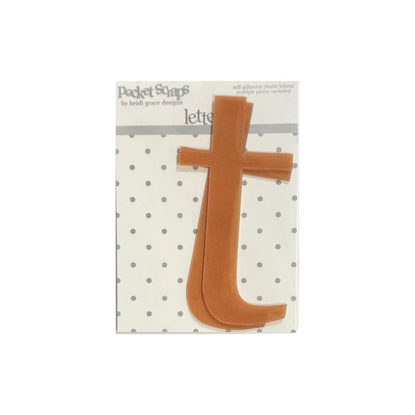 A tan plastic letter 't' from the Pocket Scaps letter set by Beth Grace Design, shown on its original white and gray polka dot backing card.