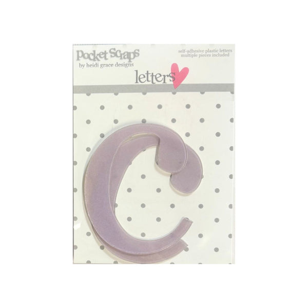 A lavender plastic letter 'C' die-cut sticker from Pocket Scaps by Heidi Grace Designs, presented on its original white card backing with a gray polka dot pattern.