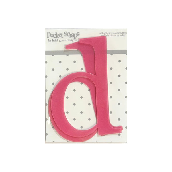 A bright pink plastic letter 'd' from the Pocket Scapes by Heidi Grace Designs self-adhesive plastic letters set, mounted on its white and gray polka dot backing card.