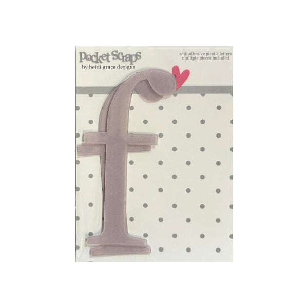 A lavender-colored plastic letter 'f' nail file from Pocket Scrap by Heidi Grace Designs, shown on its original backing card with a polka dot pattern and a small pink heart accent.