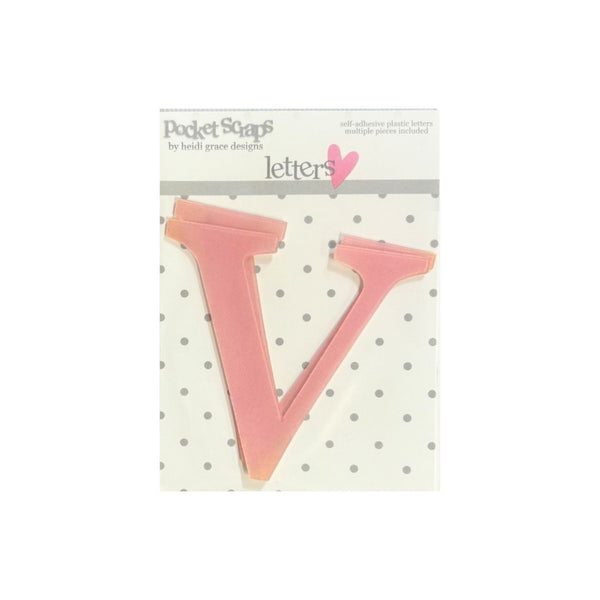 A pink plastic letter 'V' from the 'Pocket Scrap' set by Heidi Grace Design, shown in its original retail packaging with a white polka-dot backing card.