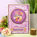 Card with a teapot design on a brick background, surrounded by flowers and plants.