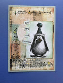 A handmade Christmas greeting card featuring a black-and-white penguin wearing a dark green pom-pom hat, with the text 'Baby it's cold outside' and decorative holiday doodles, displayed on a solid blue background.