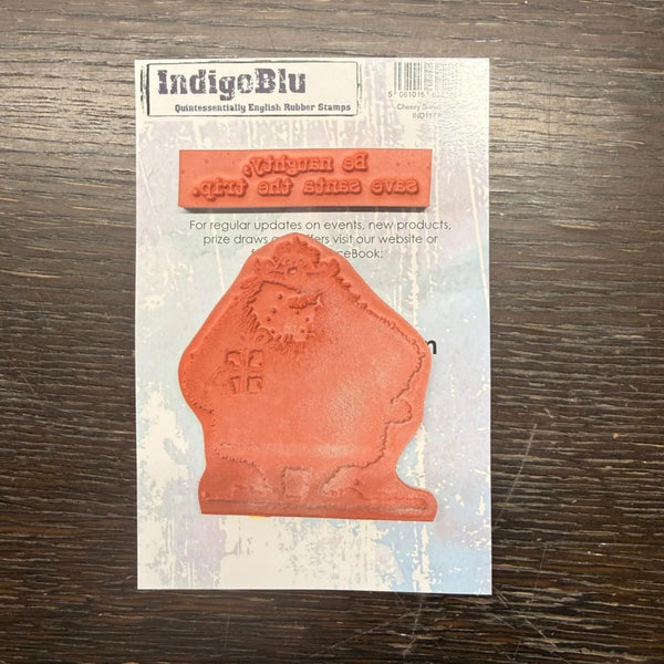 IndigeBlu rubber stamp package on a dark wood surface, showing the stamp and its printed sample text.