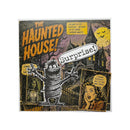 A square Halloween-themed art print or poster titled 'The Haunted House! Surprise!' featuring a spooky haunted house, a mummy figure, bats, and vintage-style illustrated faces with text bubbles, shown against a plain white background.
