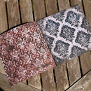 Two patterned fabric samples on a wooden surface