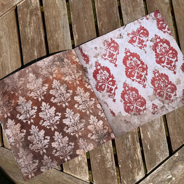 Two patterned paper sheets on a wooden surface