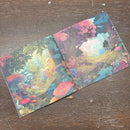Two colorful greeting cards with nature-themed designs on a wooden surface.
