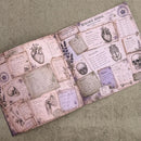 An open vintage-style research journal spread on a textured olive green fabric background. The pages are aged, pinkish-tan, and decorated with anatomical illustrations of hearts, a skull, a winged bone, handwritten notes, and botanical details like lavender.
