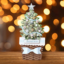 Decorative Christmas tree with ornaments on a wooden base against a blurred light background