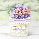 Floral arrangement in a decorative pot with 'Birthday Wishes Just for You' text on a wooden surface.