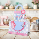 Baby shower gift basket with utensils and a baby bib on a kitchen counter.