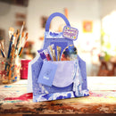 Blue art apron with paintbrushes and art supplies on a wooden table.