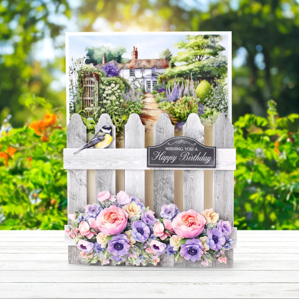 Greeting card with garden scene, flowers, and a picket fence.