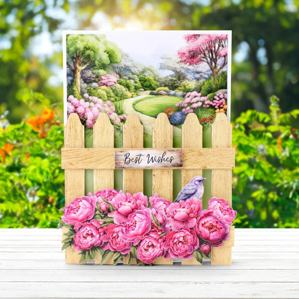Greeting card with pink flowers, a bird, and a wooden picket fence with 'Best Wishes' sign, set against a garden background.