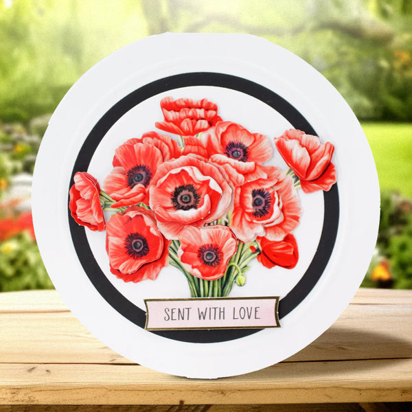 Round card with red flowers and 'Sent with Love' text on a wooden surface with a blurred natural background