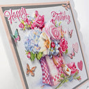 A square layered paper card with a floral bouquet in a checkered vase, pink 'Happy Birthday' script text, butterflies, hearts, and 3D pop-up flower details on a white background.