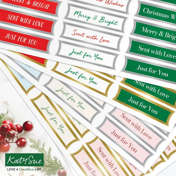 A set of decorative holiday gift tags with festive text such as 'Merry & Bright,' 'Just for You,' and 'Sent with Love' in red, green, pink, gold, and white designs. The tags are arranged on a light background with a small holiday berry illustration in the lower left.