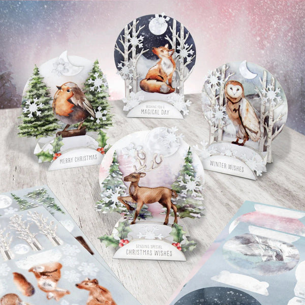 A set of Christmas-themed 3D pop-up cards featuring woodland animals like a robin, fox, owl, and deer, along with snowy trees and festive text such as 'Merry Christmas' and 'Winter Wishes', displayed on a light wooden surface with some card backings visible.