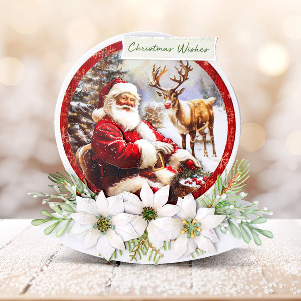 A round Christmas greeting card with a festive illustration of Santa Claus, a reindeer, and snow, displayed with white poinsettias and greenery on a snowy surface. The card reads 'Christmas Wishes' at the top.