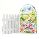 Greeting card with a scenic design featuring flowers, butterflies, and a white picket fence.