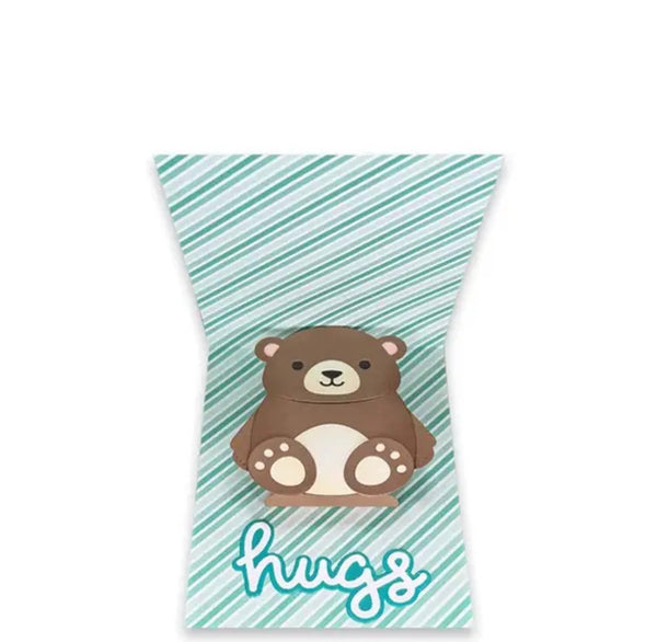A decorative gift bag or pouch with a rounded top and bottom, featuring a cartoon brown bear on a mint green and white striped background, with the word 'hugs' in cursive at the bottom.