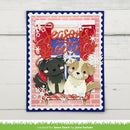 A handmade layered greeting card featuring two cute paper dogs sitting in a sleigh under a red 'Seasons Greetings' script, with white snowflakes and a pink brick pattern background, displayed on a white wood plank surface.