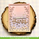 A handmade square greeting card with a pink border and laser-cut floral frame, placed on a rustic wood slice. The card reads 'sending you thanks' with small clear rhinestones, photographed on a white gingham background.