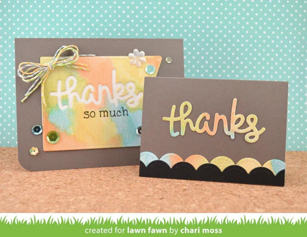 Two handmade greeting cards displayed on a cork surface against a turquoise polka-dot background. One card has a watercolor-style pastel insert with the words 'thanks so much' and a small bow; the other is dark brown with a scalloped multicolor border and a raised 'thanks' word.