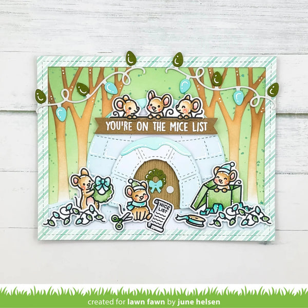 A handmade greeting card featuring a cute winter mouse scene with three mice around an igloo, decorated with green leaves, blue ornaments, and the text 'YOU'RE ON THE MICE LIST'. The card is displayed on a white wood background.
