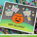 A handmade Halloween greeting card with a glittery orange jack-o'-lantern, three cute fairy cutouts, and the words “HAPPY HALLOWEEN!” on a dark gray and green background, styled with purple flowers.