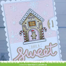 A handmade holiday greeting card featuring a gingerbread house illustration with candy canes, snowflakes, and the words 'HAVE A Sweet XMAS'. The card has scalloped white edges and is photographed against a light blue-gray wood background.