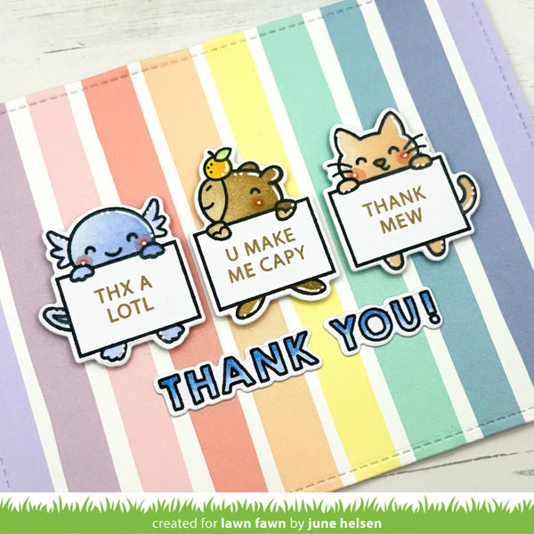 A handmade thank-you card or sticker sheet featuring three cute cartoon animal characters holding signs that read 'THX A LOTL', 'U MAKE ME CAPY', and 'THANK MEW', with large 'THANK YOU!' text below. The background has pastel vertical stripes in multiple colors, and a small credit line at the bottom reads 'created for lawn fawn by june helsen'.