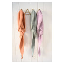 Three crochet Hooded Scarfs  in orange, green, and pink hanging on a wooden rack against a white wooden panel background.