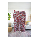 Multicolored blanket draped over a sofa in a living room setting with a plant and rug.