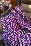 Multicolored blanket on a couch with flowers in the background