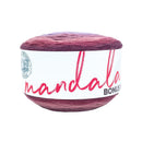 A ball of mandala yarn with a marbled color transition from deep purple to burgundy red, wrapped in a white paper label with pink script text.
