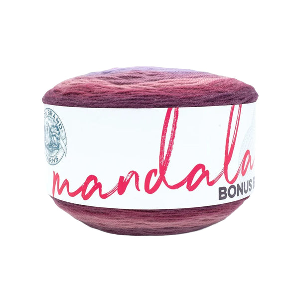 A ball of mandala yarn with a marbled color transition from deep purple to burgundy red, wrapped in a white paper label with pink script text.