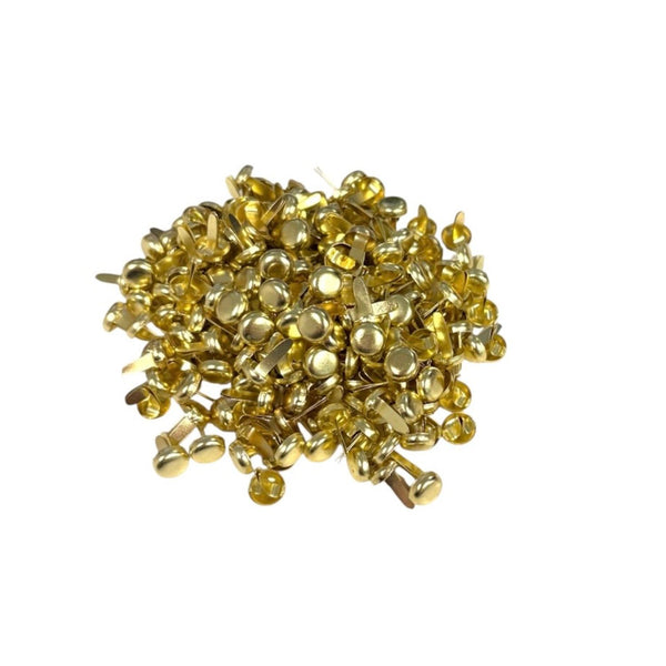 A pile of small metallic gold push pins on a plain white background.