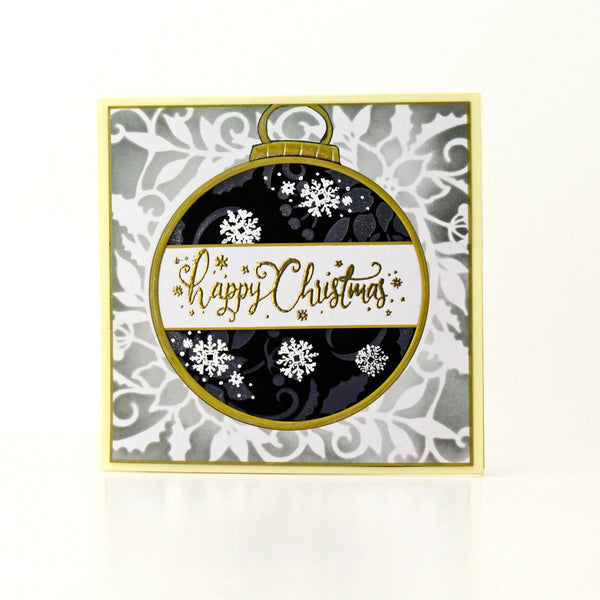 A square handmade Christmas greeting card featuring a large circular ornament design in black, white, and gold with the text 'Happy Christmas' in gold script. The card has a gold border and is photographed on a clean white background with a soft reflection.