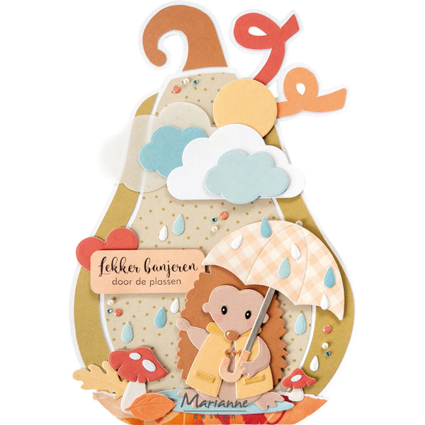 A layered paper craft pop-up card featuring a cute hedgehog holding a checkered umbrella under clouds and raindrops, with the Dutch text 'fekker banieren door de plassen' and the name 'Marianne'.