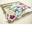 A handcrafted layered paper collage featuring a winter holiday scene with a snowman, evergreen trees, poinsettias, and decorative scalloped edges. The card is photographed on a light beige background with a 'Marianne design' watermark visible in the lower left.