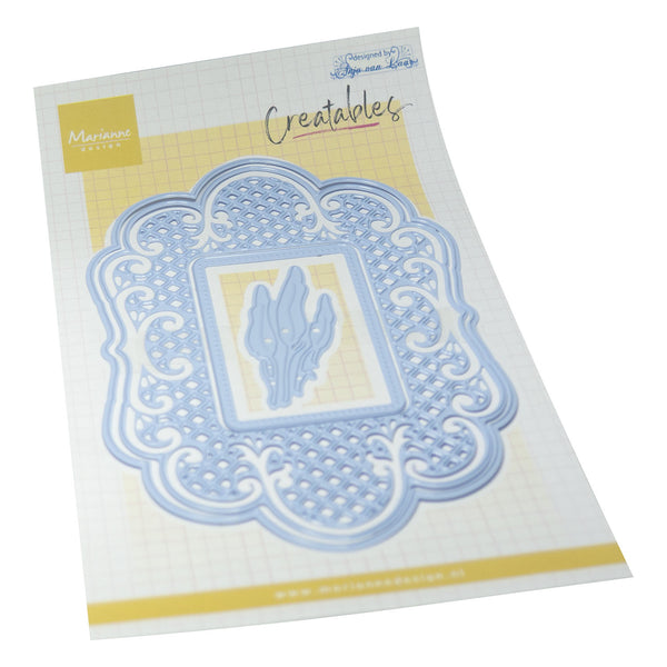 A packaged crafting die set from Marijana Creations, featuring a light blue ornate die-cut pattern on a white and yellow grid backing card. The package is angled on a plain white background.