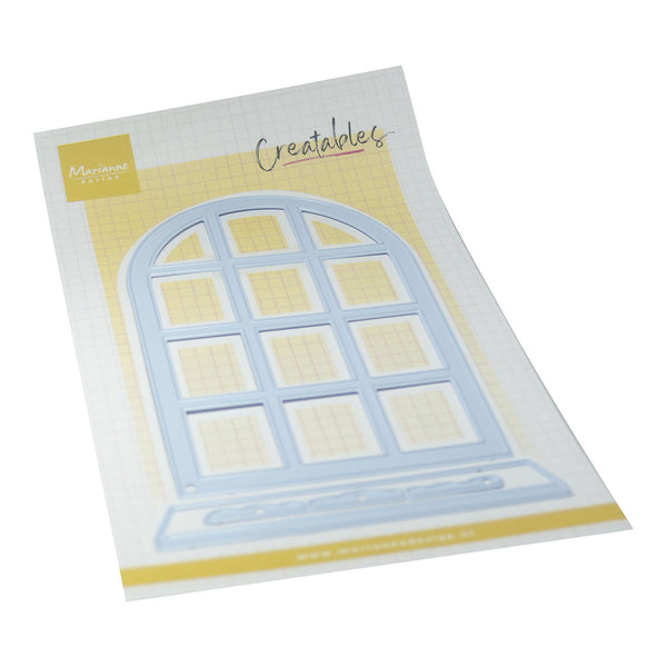 A packaged craft die set from Creations by Marianne, featuring an arched window-shaped die on a white gridded backing card with yellow accents.