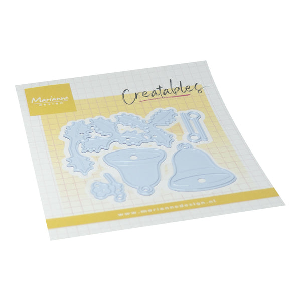 Marianne Design 'Creatables' die-cut craft kit on a white background. The kit includes light blue metal dies shaped like a Christmas wreath, a bell, a key, and a small ornament, mounted on a white grid card with yellow borders and the 'Marianne Design' logo.