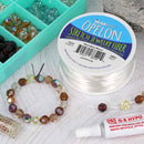 Opelon Stretch Jewelry Fiber spool with beaded bracelet and crystals on a white surface