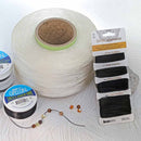 A large spool of white cord or thread sits on a light surface, with several smaller spools and a carded package of black cord labeled BeadSmith Basics Elements OptionL. A few loose beads and a thin cord with beads are placed in front.