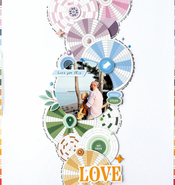 A vertical scrapbook page layout featuring layered circular paper fans, green leaves, a small photo of a couple by the beach, decorative text labels, and the word 'LOVE' in orange at the bottom, all arranged on a white background.